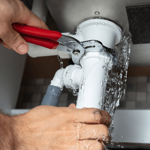 Reliable Plumbing Repairs in Johannesburg 2 Sisters Plumbing technician fixing a leaking pipe under a sink in Johannesburg.